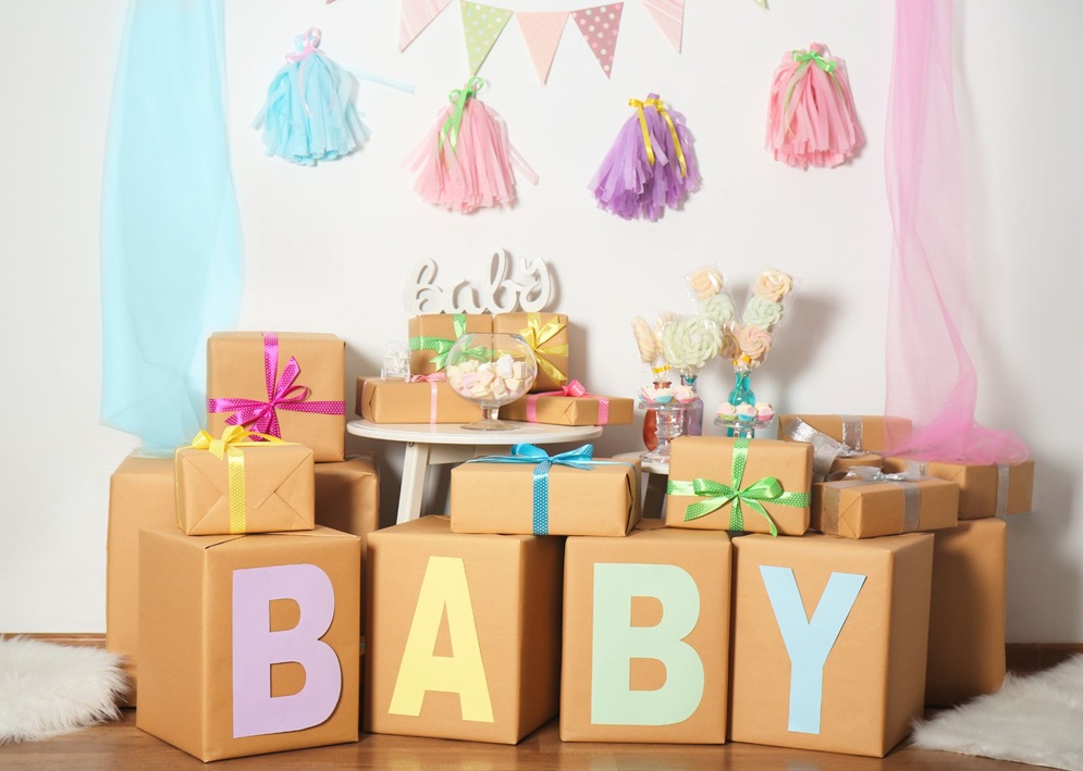 Stacked pastel boxes spelling BABY with wrapped gifts, marshmallows, tassels, and festive bunting.