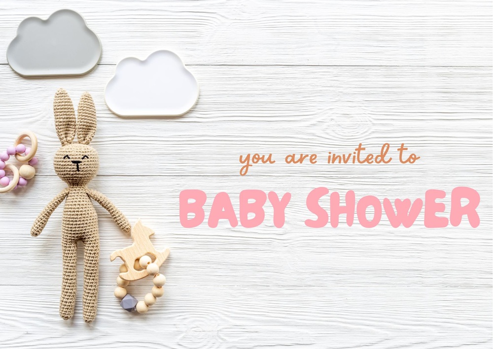 White wooden background with bunny toy, rocking horse teether, beads, and bold pink baby shower text.