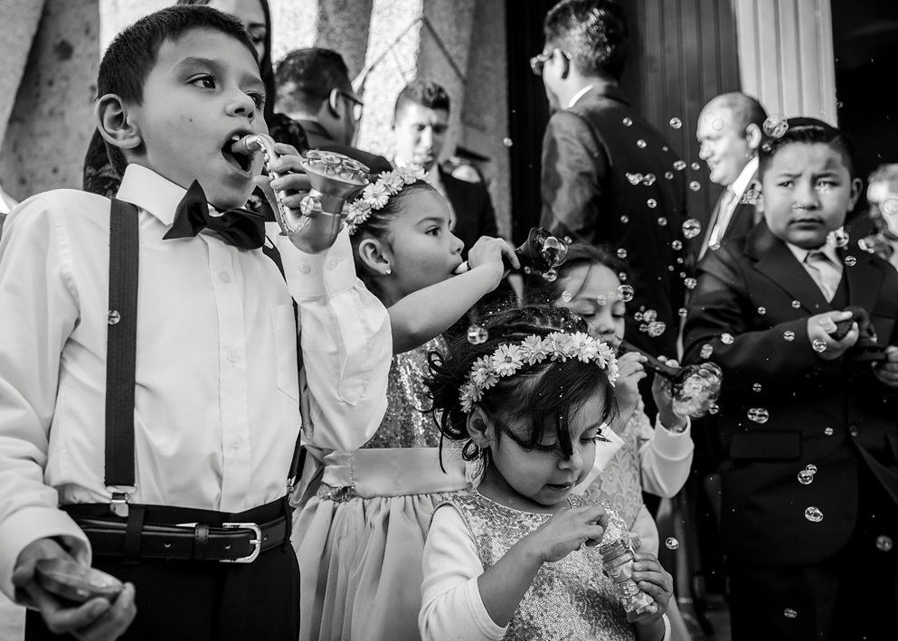 Children in formal attire blowing bubbles at wedding ceremony, fun activity for young guests