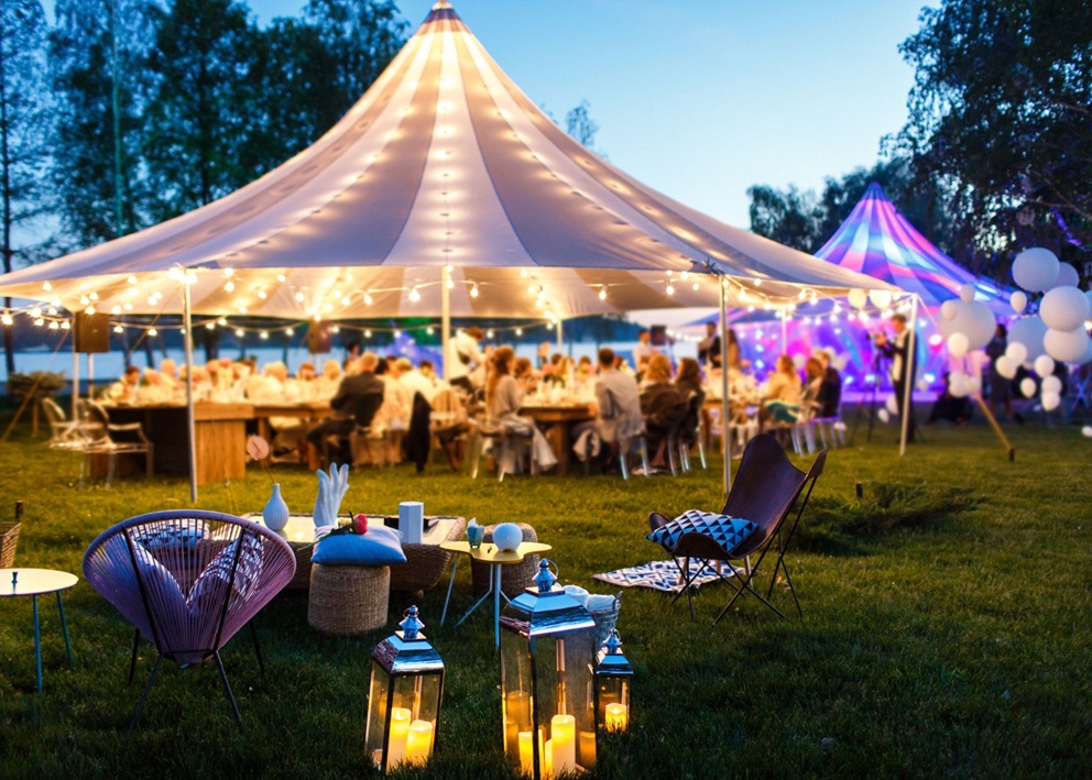 Elegant outdoor wedding reception tent with lighting and seating for guests and families