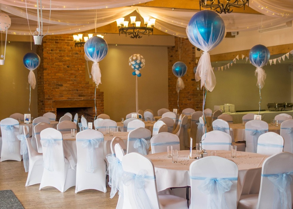 Elegant reception hall with white chair covers, blue sashes, and floating blue balloons with tulle decorations