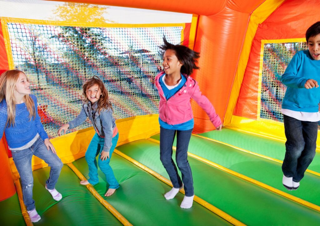 Kids bounce together inside an inflatable playhouse with bright walls and cushioned floors.