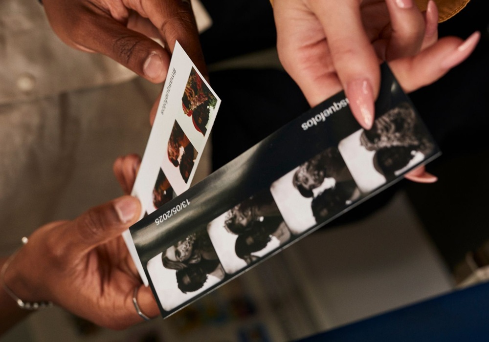 Hands hold a photo strip print, showing candid moments from the booth.