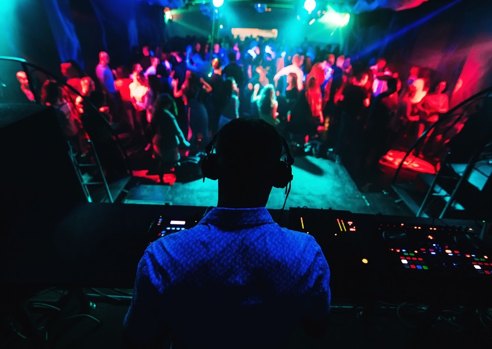 DJ mixes music for a lively crowd under colorful lights, creating exciting Bar Mitzvah entertainment.
