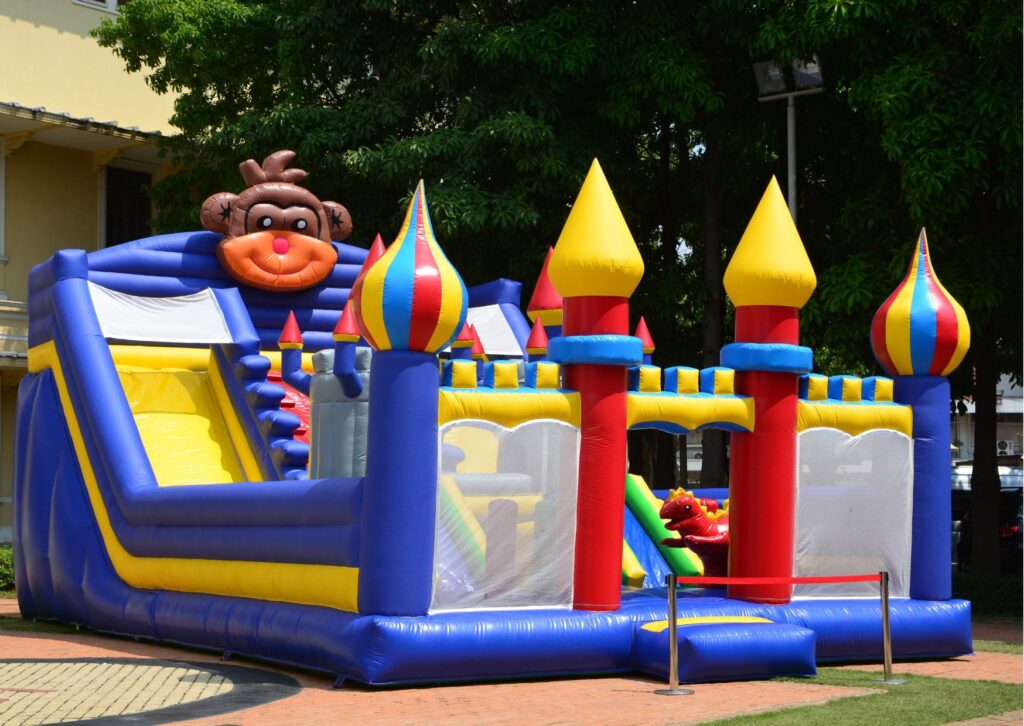 Colorful castle themed inflatable bounce house with towers, slides, and decorative character details.